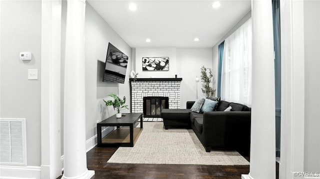 1323 Avondale Ave, Richmond, VA 23227 - living area featuring a brick fireplace, recessed lighting, wood finished floors, and decorative columns