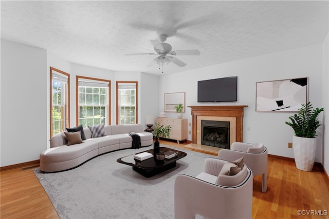 6768 Poplar Woods Ct, Quinton, VA 23141 - living area featuring light wood-style floors, a fireplace with flush hearth, a ceiling fan, and a textured ceiling