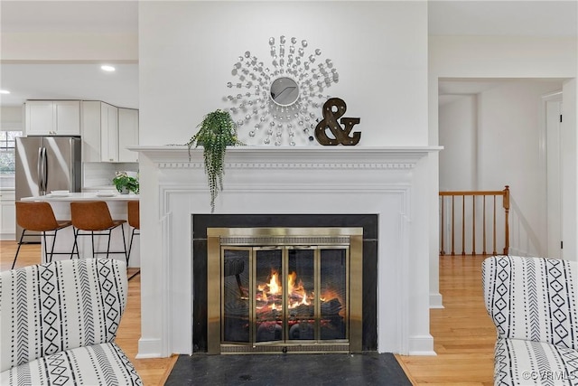 4029 Old Buckingham Rd, Powhatan, VA 23139 - detailed view of a fireplace with flush hearth, freestanding refrigerator, wood finished floors, and recessed lighting