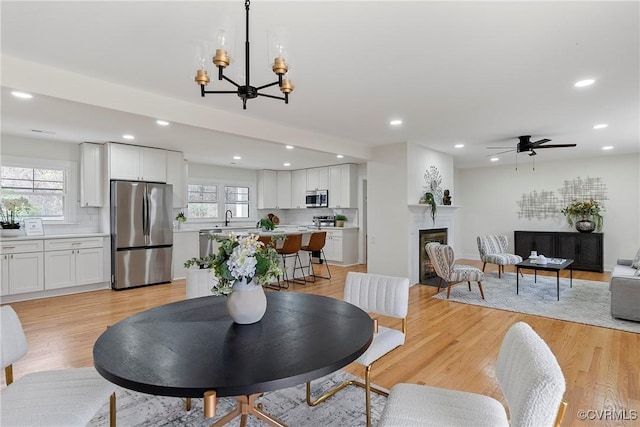 4029 Old Buckingham Rd, Powhatan, VA 23139 - dining space featuring recessed lighting, a chandelier, a glass covered fireplace, ceiling fan, and light wood-style flooring