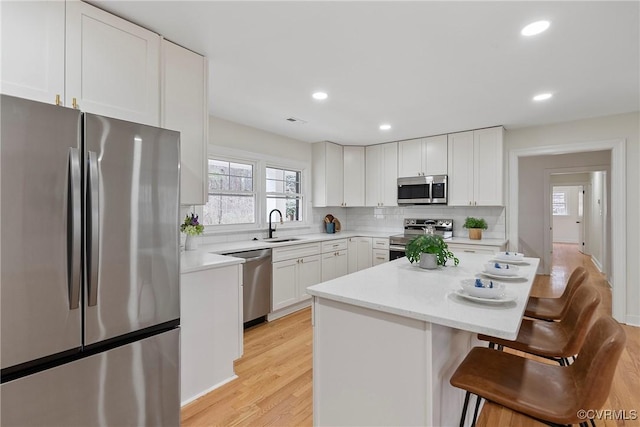 4029 Old Buckingham Rd, Powhatan, VA 23139 - kitchen featuring stainless steel appliances, a kitchen bar, decorative backsplash, light countertops, and light wood finished floors