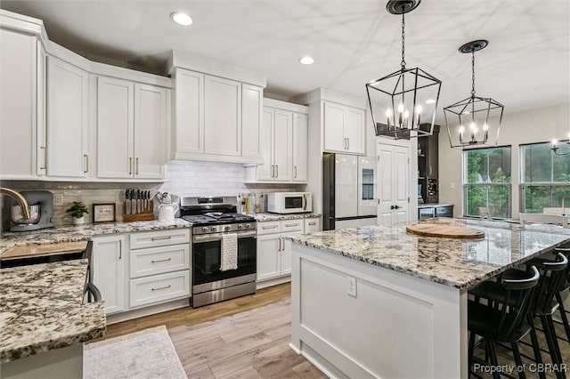 4217 Pillar, Williamsburg, VA 23188 - kitchen featuring refrigerator, stainless steel range with gas stovetop, white microwave, a chandelier, and white cabinetry