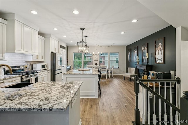 4217 Pillar, Williamsburg, VA 23188 - kitchen with gas stove, a kitchen island, recessed lighting, white cabinetry, and refrigerator