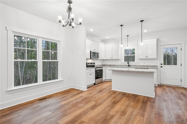 2467 Judes Ferry Rd, Powhatan, VA 23139 - kitchen with appliances with stainless steel finishes, white cabinetry, light wood-style flooring, a chandelier, and a center island