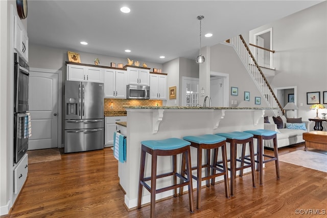 1638 Olde Links Dr, Powhatan, VA 23139 - kitchen with appliances with stainless steel finishes, a kitchen bar, dark wood-style floors, tasteful backsplash, and recessed lighting