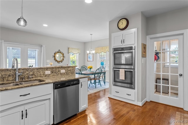 1638 Olde Links Dr, Powhatan, VA 23139 - kitchen featuring appliances with stainless steel finishes, light stone countertops, light wood finished floors, white cabinetry, and pendant lighting