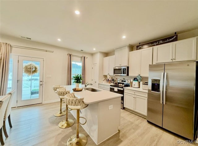 2007 Turtle Pkwy, Henrico, VA 23150 - kitchen featuring appliances with stainless steel finishes, light wood-style flooring, white cabinetry, a center island with sink, and a kitchen bar