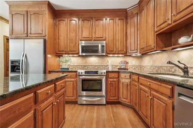 2019 Hornes Lake Rd, Williamsburg, VA 23185 - kitchen featuring appliances with stainless steel finishes, decorative backsplash, dark stone counters, brown cabinets, and light wood-style flooring