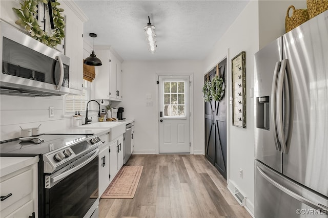 453 Manquin Dr, King William, VA 23009 - kitchen with appliances with stainless steel finishes, white cabinets, light wood-style floors, light countertops, and a textured ceiling
