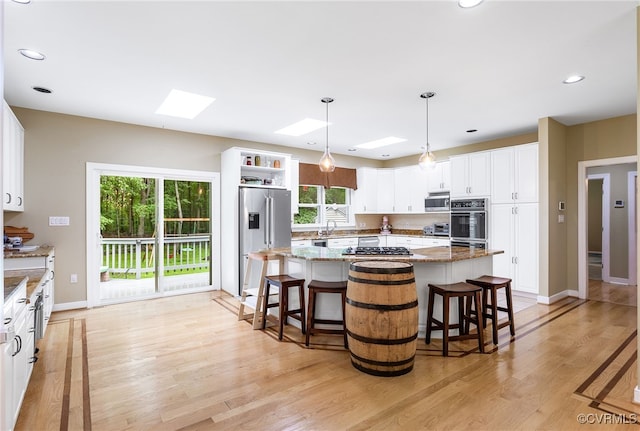 10598 Lambeth Rd, Glen Allen, VA 23060 - kitchen featuring stainless steel appliances, a skylight, light wood finished floors, open shelves, and light stone counters