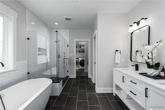 2114 N Ave, Richmond, VA 23222 - full bath featuring washing machine and dryer, a soaking tub, double vanity, a stall shower, and tile patterned floors