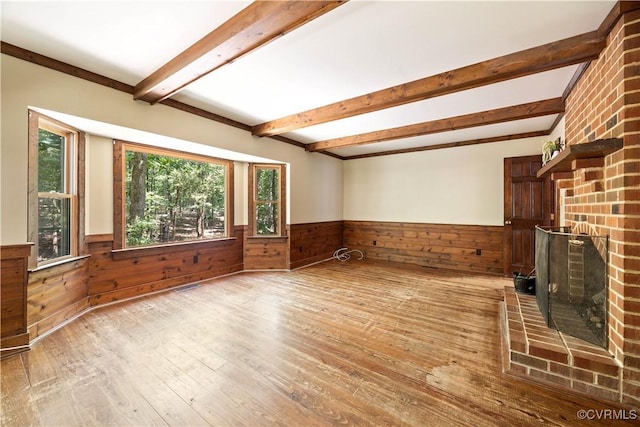 3180 Judes Ferry Rd, Powhatan, VA 23139 - unfurnished living room featuring wainscoting, hardwood / wood-style floors, beam ceiling, wooden walls, and a brick fireplace