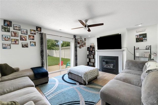 3706 Paul Karnes Dr, Hopewell, VA 23860 - living room featuring ceiling fan, wood finished floors, a glass covered fireplace, and a textured ceiling