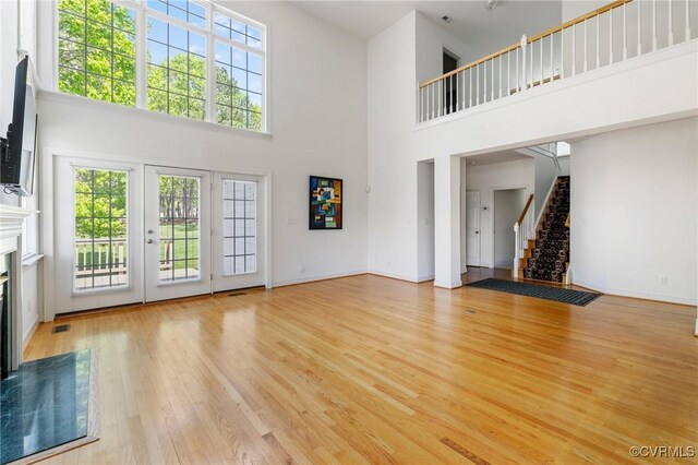 5908 Dominion Fairways Ct, Glen Allen, VA 23059 - unfurnished living room featuring a high end fireplace, a towering ceiling, stairway, and light wood finished floors