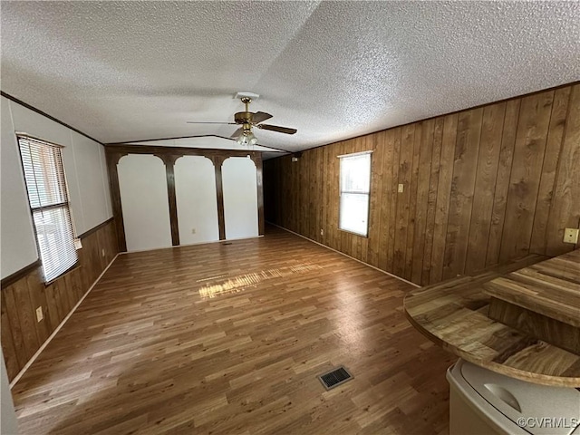 2305 Swift Bluff Dr, South Chesterfield, VA 23834 - unfurnished living room featuring wood finished floors, ceiling fan, wooden walls, a textured ceiling, and a wainscoted wall