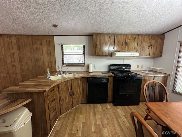 2305 Swift Bluff Dr, South Chesterfield, VA 23834 - kitchen with black appliances, brown cabinets, light wood-style floors, a textured ceiling, and under cabinet range hood