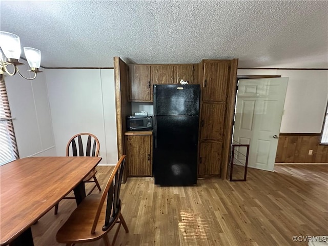 2305 Swift Bluff Dr, South Chesterfield, VA 23834 - kitchen with black appliances, light wood finished floors, a textured ceiling, a chandelier, and brown cabinetry