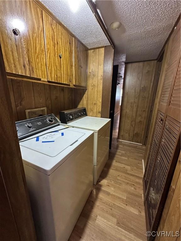 2305 Swift Bluff Dr, South Chesterfield, VA 23834 - laundry room featuring cabinet space, washer and dryer, light wood-style flooring, wooden walls, and a textured ceiling