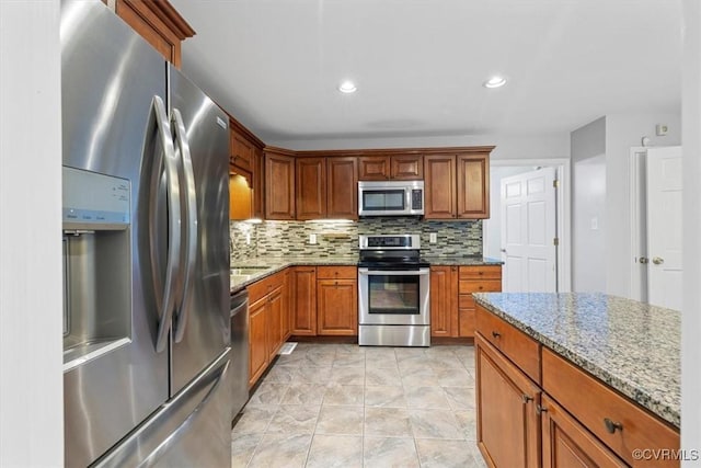 12628 Copperas Ln, Richmond, VA 23233 - kitchen featuring appliances with stainless steel finishes, tasteful backsplash, stone countertops, brown cabinets, and recessed lighting