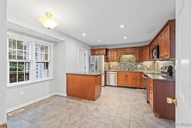 12628 Copperas Ln, Richmond, VA 23233 - kitchen featuring stainless steel appliances, tasteful backsplash, dark stone countertops, brown cabinets, and recessed lighting
