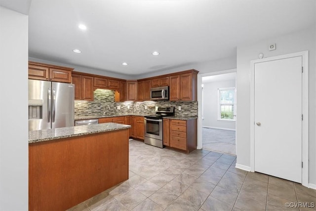 12628 Copperas Ln, Richmond, VA 23233 - kitchen featuring appliances with stainless steel finishes, light stone counters, tasteful backsplash, brown cabinetry, and recessed lighting