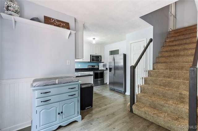 2708 Pineridge Ln, Powhatan, VA 23139 - kitchen with stainless steel appliances, light wood-style floors, a wainscoted wall, white cabinetry, and dark countertops