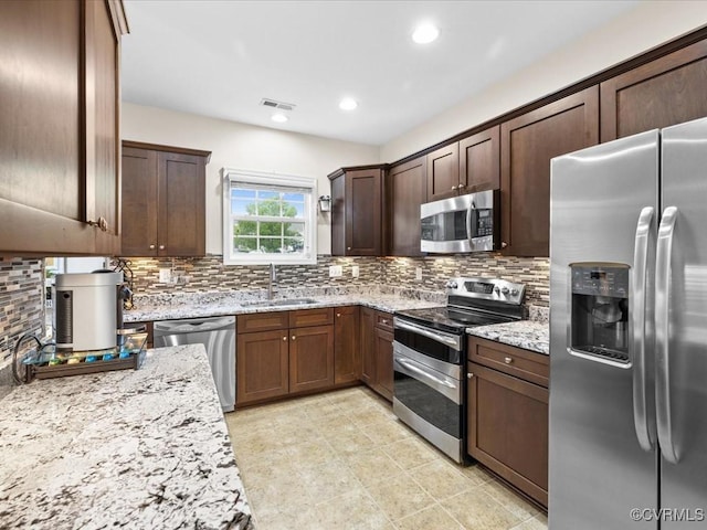 17318 Library Blvd, Ruther Glen, VA 22546 - kitchen featuring stainless steel appliances, decorative backsplash, light stone countertops, dark brown cabinetry, and recessed lighting