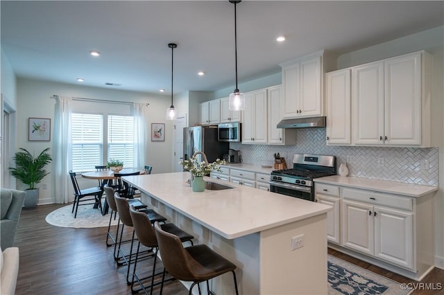 6448 Twin Falls Ter, Moseley, VA 23120 - kitchen with stainless steel appliances, under cabinet range hood, decorative backsplash, a kitchen island with sink, and white cabinetry