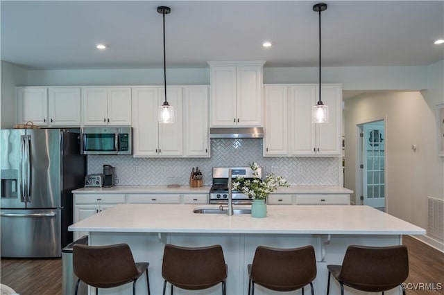 6448 Twin Falls Ter, Moseley, VA 23120 - kitchen with stainless steel appliances, under cabinet range hood, white cabinetry, dark wood-style flooring, and backsplash