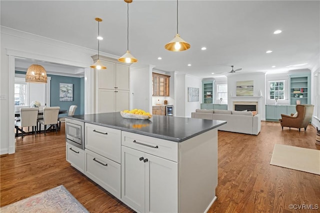 4705 Fitzhugh Ave, Richmond, VA 23230 - kitchen with dark countertops, ornamental molding, stainless steel microwave, white cabinets, and a fireplace