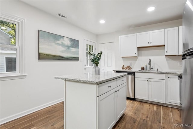 5720 Centerville Rd, Williamsburg, VA 23188 - kitchen with dishwasher, wood finished floors, white cabinets, a center island, and light stone countertops
