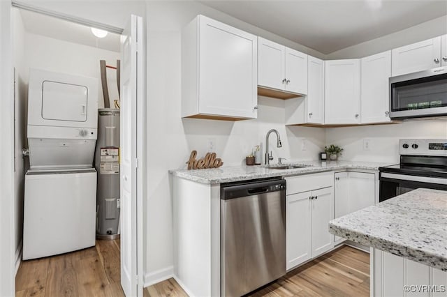 5720 Centerville Rd, Williamsburg, VA 23188 - kitchen with stainless steel appliances, stacked washer / drying machine, light wood-style floors, and white cabinets