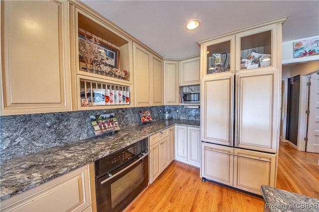 11 Franklin St, Deltaville, VA 23043 - kitchen with cream cabinets, black oven, decorative backsplash, light wood-type flooring, and recessed lighting