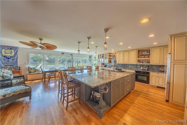 11 Franklin St, Deltaville, VA 23043 - kitchen with black oven, open shelves, a kitchen bar, freestanding refrigerator, and decorative backsplash