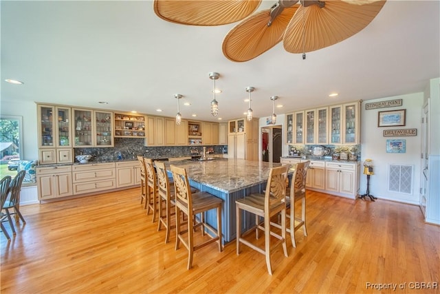 11 Franklin St, Deltaville, VA 23043 - kitchen featuring decorative backsplash, recessed lighting, a kitchen bar, a large island, and glass insert cabinets