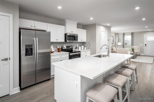 2254 Palm Ct, Sandston, VA 23150 - kitchen with appliances with stainless steel finishes, light wood-style floors, white cabinets, a kitchen island with sink, and recessed lighting