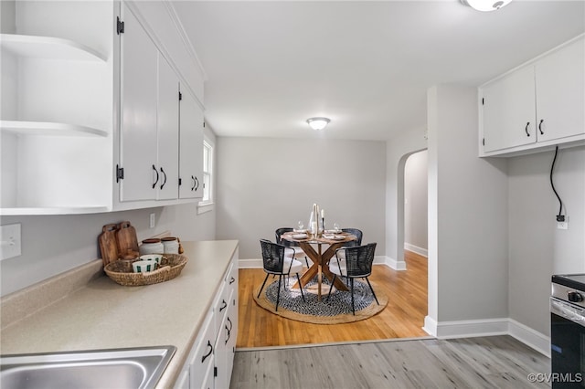 4308 Sunset Dr, North Dinwiddie, VA 23803 - kitchen with arched walkways, stainless steel range oven, white cabinets, and light wood-style flooring