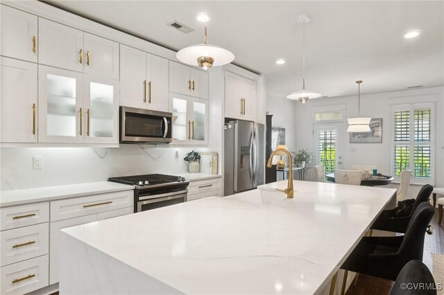 14424 Michaux Village Dr, Midlothian, VA 23113 - kitchen featuring appliances with stainless steel finishes, white cabinets, a center island with sink, a kitchen breakfast bar, and decorative light fixtures