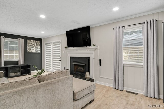 14210 Cherry St, Chester, VA 23831 - living area with a textured ceiling, crown molding, light wood-style flooring, a fireplace with flush hearth, and recessed lighting