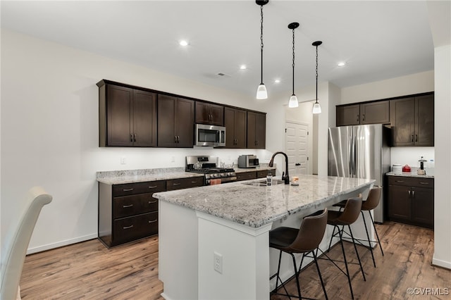 18325 Palisades Ct, Moseley, VA 23120 - kitchen with stainless steel appliances, light wood finished floors, dark brown cabinets, a breakfast bar area, and recessed lighting