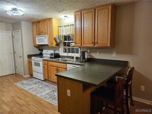 4740 Old Williamsburg Rd, Sandston, VA 23150 - kitchen with white appliances, dark countertops, light wood-style floors, and brown cabinets