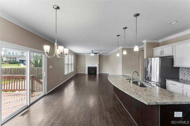 17412 Trevino Pkwy, Moseley, VA 23120 - kitchen featuring stainless steel fridge, a fireplace, dark wood-style floors, a chandelier, and white cabinetry