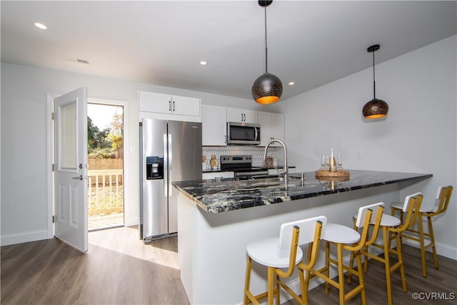 623 Pegram St, Petersburg, VA 23803 - kitchen featuring appliances with stainless steel finishes, wood finished floors, dark stone counters, a peninsula, and pendant lighting