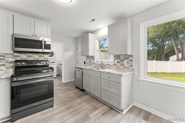 10500 Claybar Trl, North Chesterfield, VA 23236 - kitchen featuring estacked washer and dryer, stainless steel appliances, light wood-style floors, and backsplash