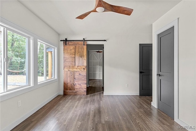 113 Rappa Run Rd, Topping, VA 23169 - unfurnished bedroom featuring multiple windows, dark wood-style flooring, and a barn door