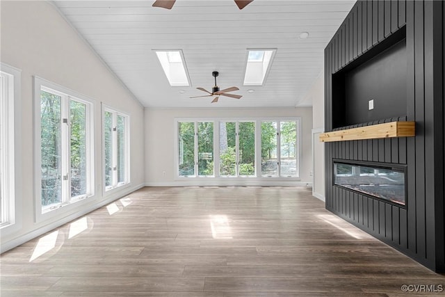 113 Rappa Run Rd, Topping, VA 23169 - unfurnished living room featuring lofted ceiling, ceiling fan, a skylight, a glass covered fireplace, and wood finished floors
