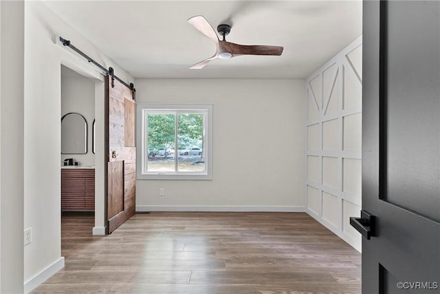 113 Rappa Run Rd, Topping, VA 23169 - unfurnished bedroom featuring a barn door, light wood-style flooring, and ceiling fan