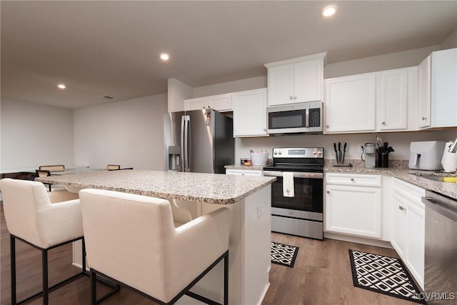 6740 Edith Oaks Way Unit 6740, Chesterfield, VA 23234 - kitchen with appliances with stainless steel finishes, a center island, light wood-style floors, white cabinets, and light stone counters