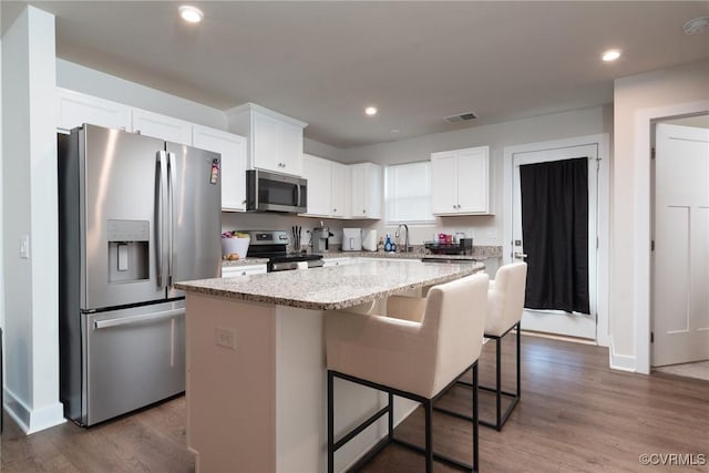 6740 Edith Oaks Way Unit 6740, Chesterfield, VA 23234 - kitchen featuring appliances with stainless steel finishes, a center island, white cabinets, a breakfast bar area, and recessed lighting