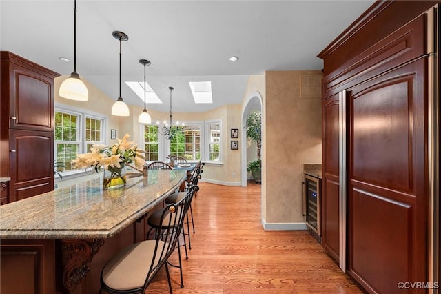 5911 Waters Edge Rd, Midlothian, VA 23112 - kitchen featuring paneled fridge, a breakfast bar, a skylight, light wood finished floors, and healthy amount of natural light